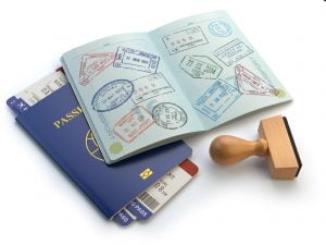 A photo of an open stamped passport lying on top of a closed passport with a pair of boarding passes closed inside of it