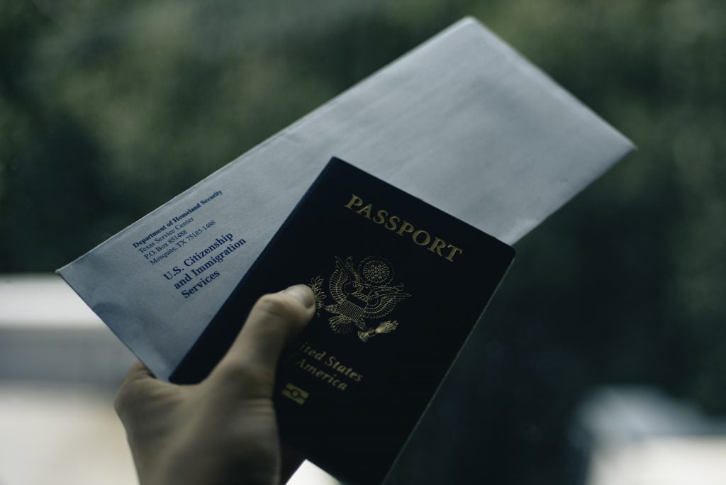 Picture of a man holding a U.S. Citizenship envelope and a passport in his hand