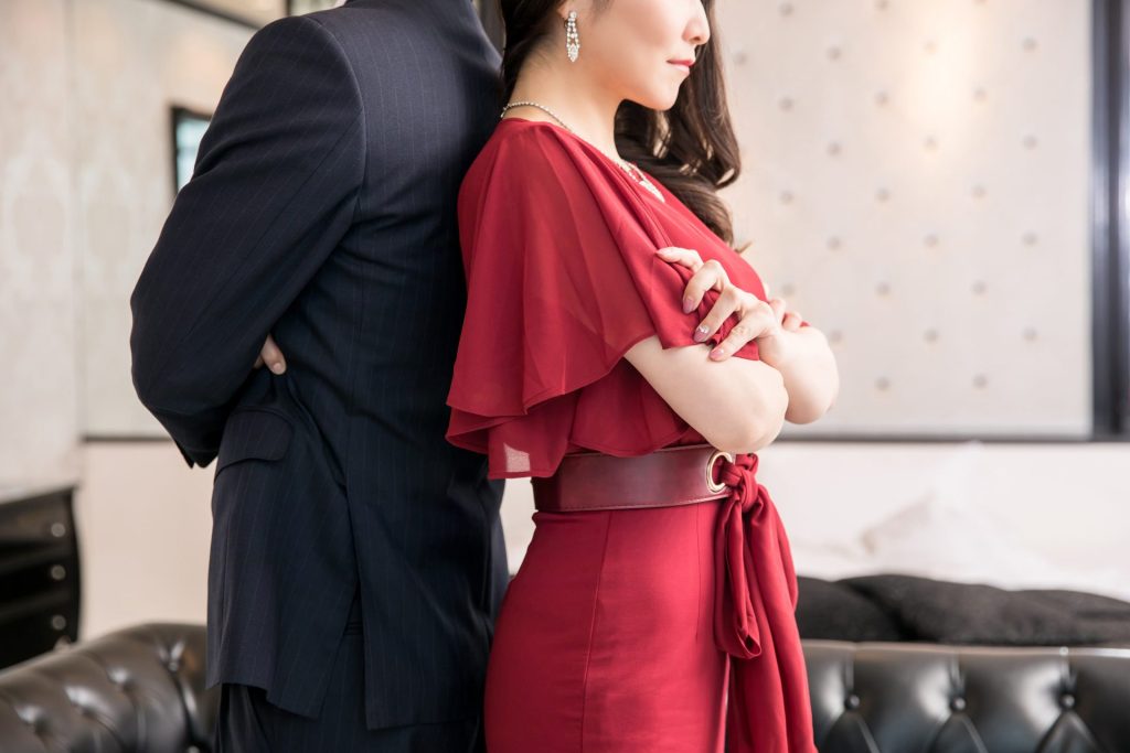 man and woman in designer clothes standing back to back with arms crossed