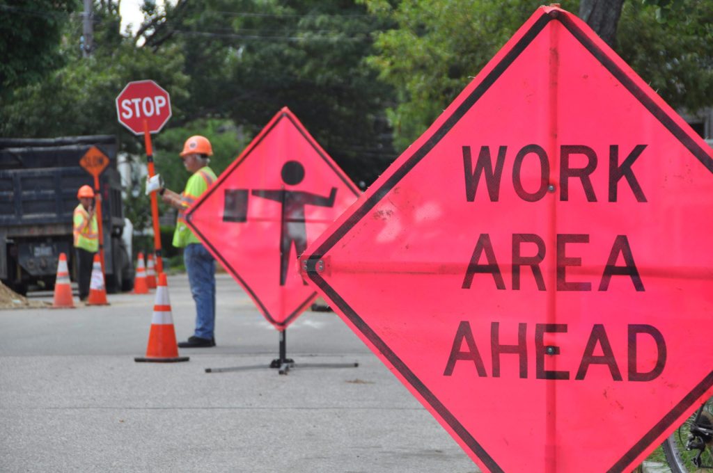 Road Work Ahead Signs and a construction worker holding up a stop sign