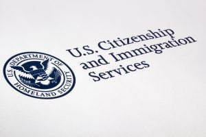 Logo of U.S. Citizenship and Immigration Services. Logo is dark blue and white