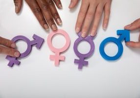 An Overhead View Of Multiethnic People Holding Different Type Of Gender Sign On White Table