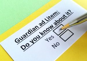 close up of a question: guardian ad litem: do you know about it? typed on a piece of white paper with yes and no check boxes with a pen hovering over the yes check box.