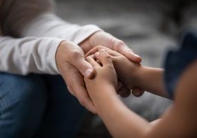 Close up compassionate parent holding hands of little kid girl
