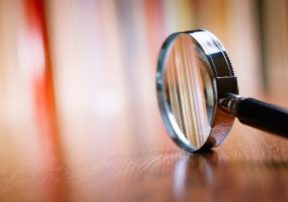 Close up Single Magnifying Glass with Black Handle, Leaning on the Wooden Table at the Office.