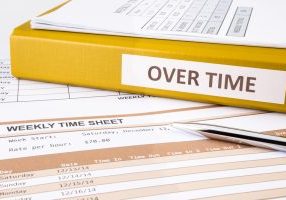 Overtime words on document binder place on blank weekly time sheets