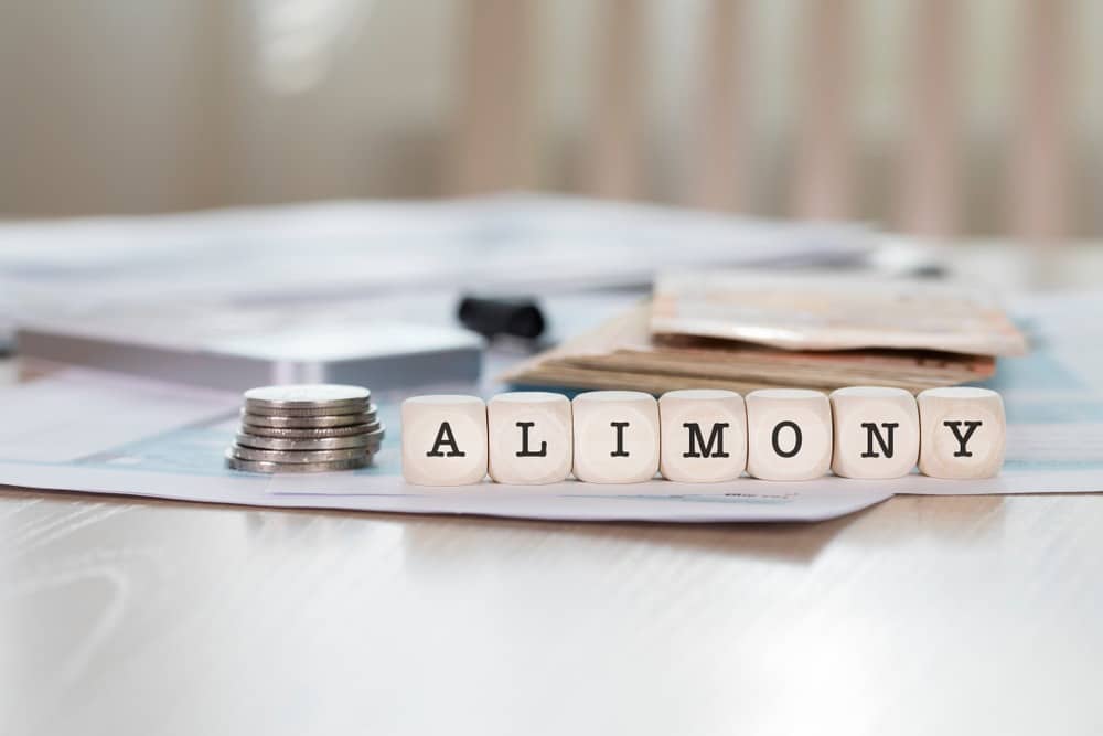 Word,Alimony,Composed,Of,Wooden,Letters.,Closeup with stack of coins