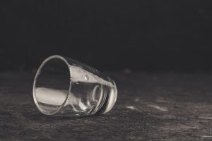 close up of an empty shot glass on its side against a dark background