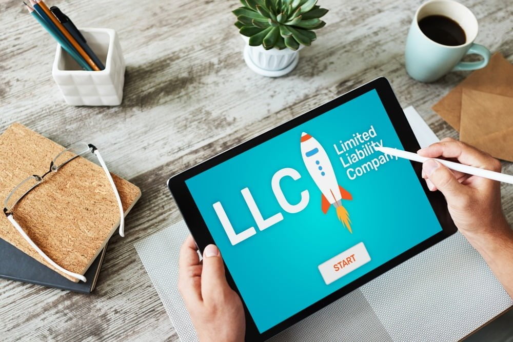 iPad with graphic of an LLC logo on a wooden table.