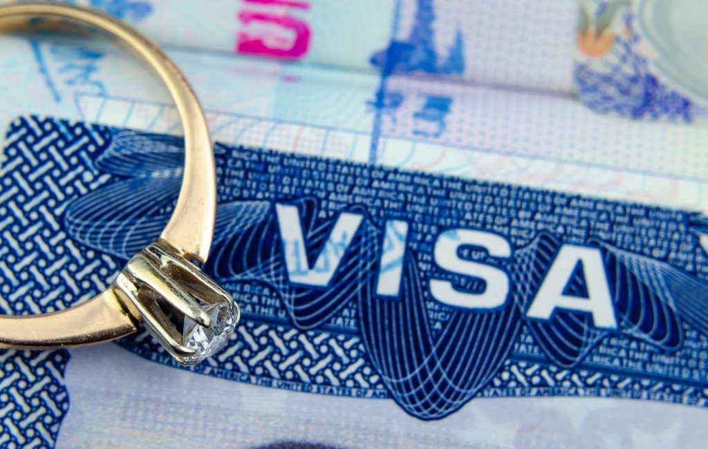 Engagement ring on top of blurred US entry visa sticker in a passport