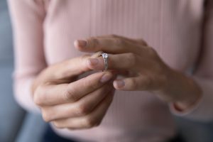 Close up young woman taking off wedding ring