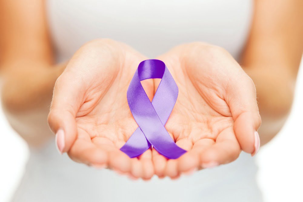 healthcare and social problems concept - womans hands holding purple domestic violence awareness ribbon