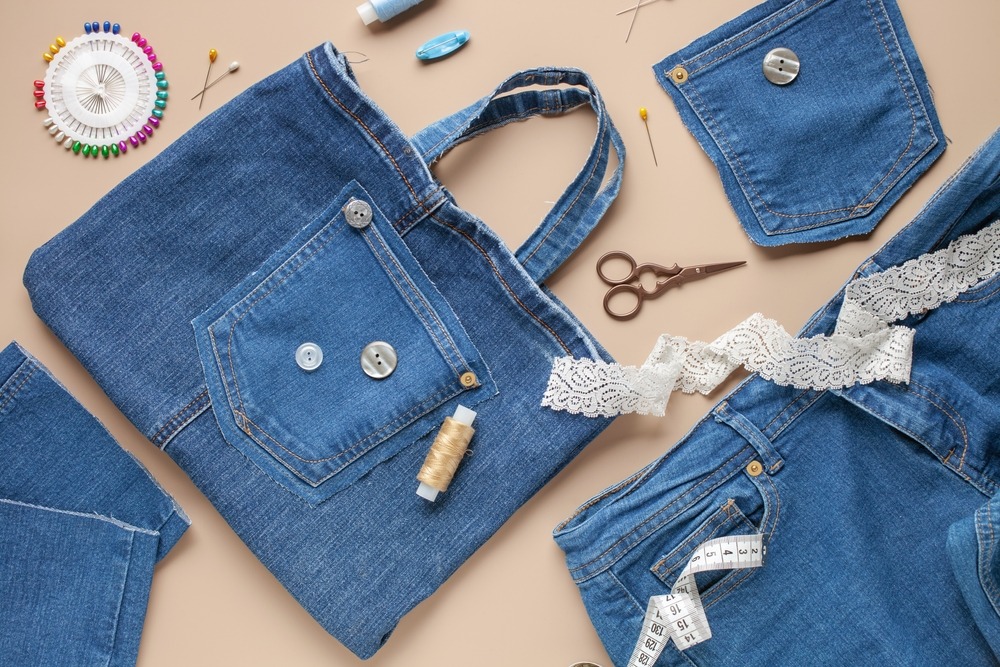 Old jeans and denim bag with sewing accessories. Top view. Recycling concept. Crafting with denim.