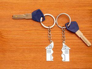 Two keys with split house matching keychains on a wooden table. Splitting assets in a divorce.