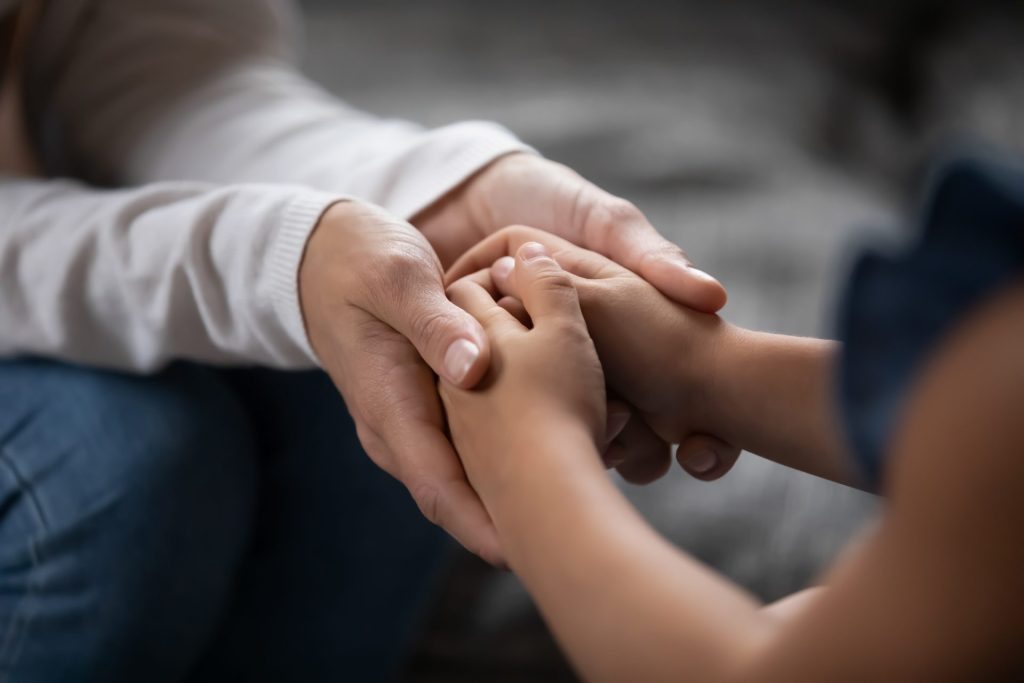 Close up compassionate parent holding hands of little kid girl