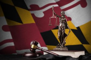 Maryland US state flag with statue of lady justice, constitution and judge hammer on black drapery. Concept of judgement and punishment