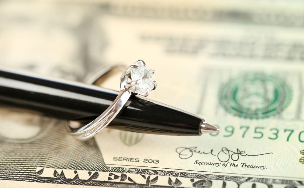 Wedding ring on pen, on banknotes background