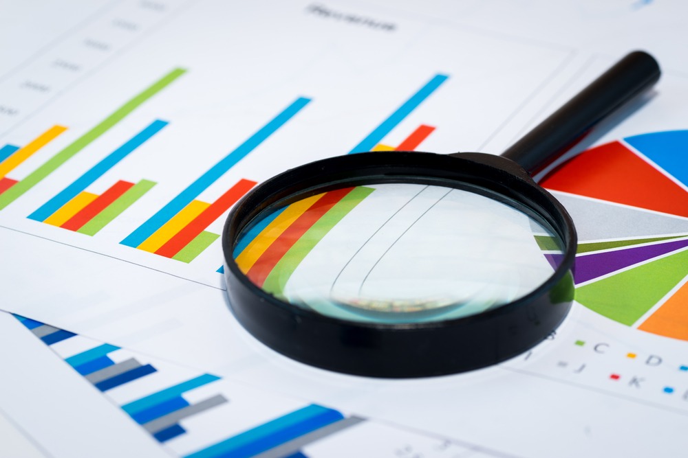 magnifying glass on papers with colorful graphs and spreadsheets