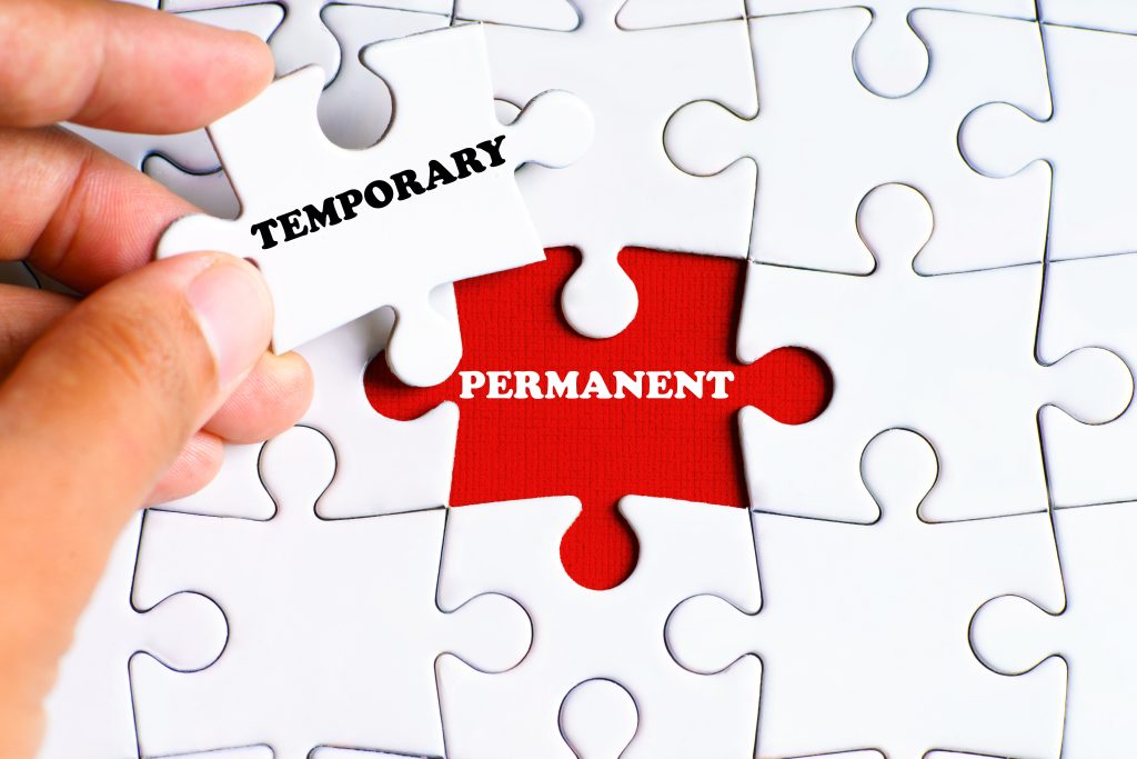 PERMANENT (word) on missing puzzle piece with a hand hold a piece that says TEMPORARY