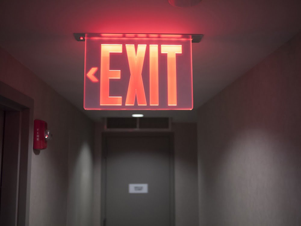 EXIT sign hanging from the ceiling in bright red letters