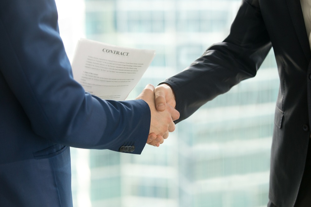 Businessmen handshaking, male hands shaking, holding contract on city building background, employment and hiring, enterprisers making good business deal after successful negotiations, close up view