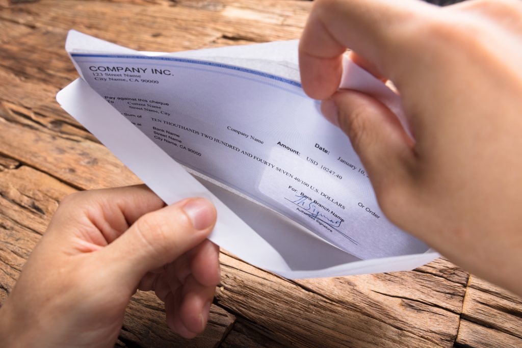 hands of businessman opening envelope with paycheck